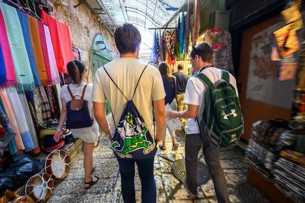 Two students walking through an alley market in Jerusalem